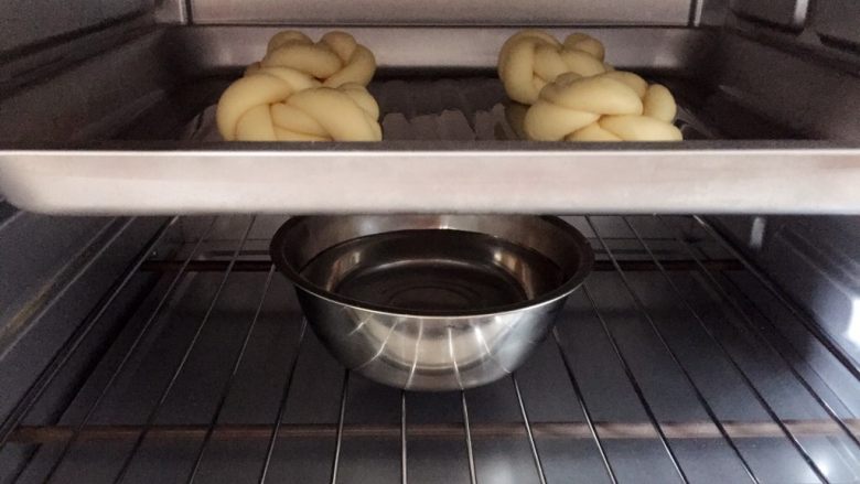 牛奶黑芝麻小餐包,把烤盘放入烤箱，烤箱里放盆热水，进行二次发酵。