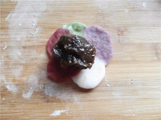 天然彩色冰皮月饼,用擀面杖将饼皮擀成中间厚、周围薄，将25克枣泥馅放饼皮中间（桌面撒少粉熟糯米粉）。