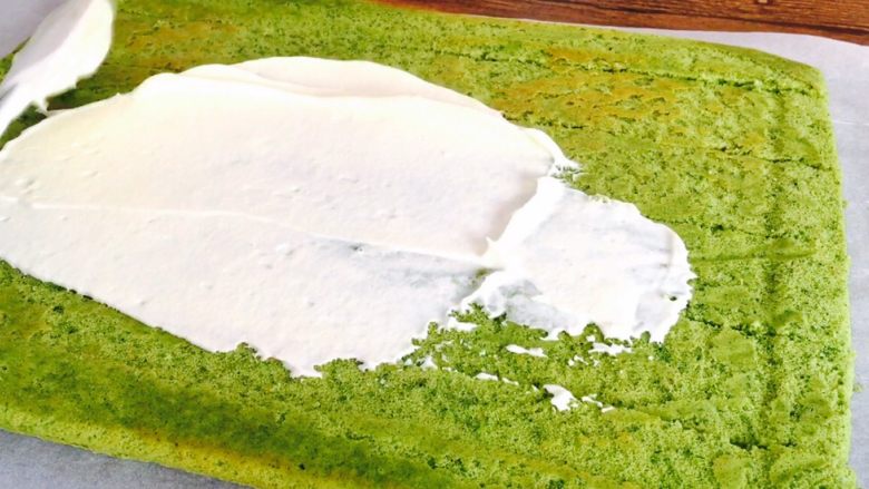 抹茶漩涡蛋糕,将部分奶油涂抹在蛋糕片上