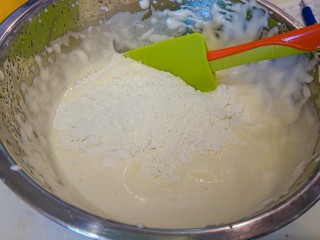 萌の檸檬小蛋糕,加入过筛的低筋面粉，用刮刀以十字刀方式輕輕的翻拌，直到看不到粉末。