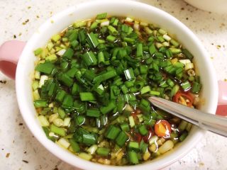 #辣菜#凉拌鲫鱼,将葱绿和韭菜绿色段放入调味汁拌匀。提前放一起腌制容易变色，可以最后再放。