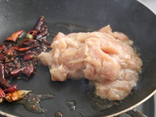 宫保鸡丁,锅中放油，炒香辣椒、花椒，放到锅一边，放入腌制好的鸡胸肉。