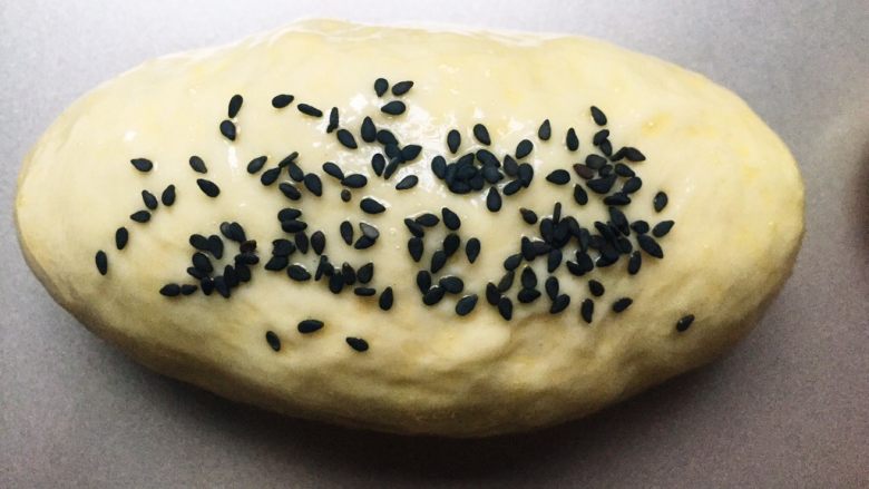 甜味-螺旋坚果面包,给二次发酵好的面包表面涂一层蛋液，撒上黑芝麻。然后烤箱170度预热10分钟，放入面包，170度上下火烤18-20分钟，最后几分钟需要盖锡纸以防表皮烤焦，要随时注意查看。