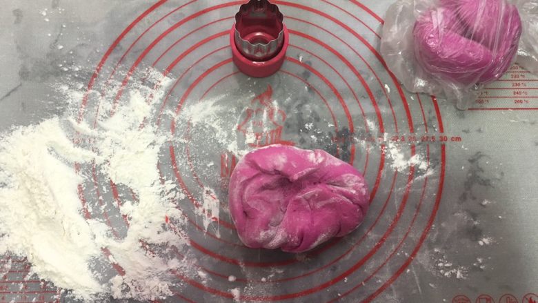 自制火龙果面,案板上洒写干粉，把面团分成2份，一份用保鲜袋装着