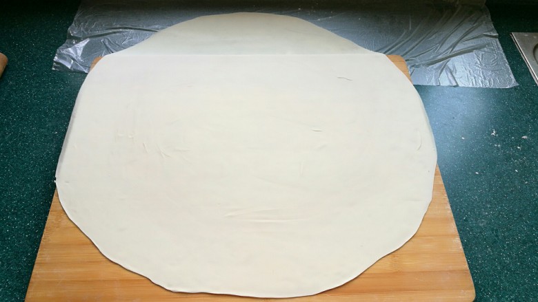 石蛤蟆水饺（博山水饺的包法）,一直擀成厚薄均匀的圆形大面皮。然后往上面撒一些面粉防沾。