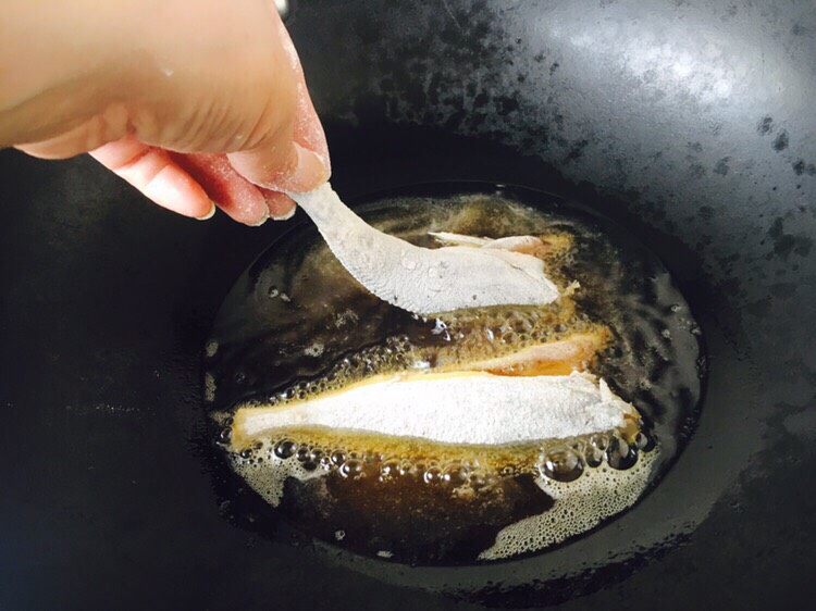 #咸味# 砂锅小黄鱼炖豆腐,锅里放适量的油，油5、6成热时拎着鱼尾轻轻的贴着油面放到锅里。