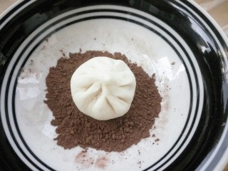 #甜味#蘑菇豆沙包,放在可可粉上，晃动盘子也好，转动包子也行，使包子的背面均匀沾上可可粉，边缘也要沾到，多余的粉抖下去