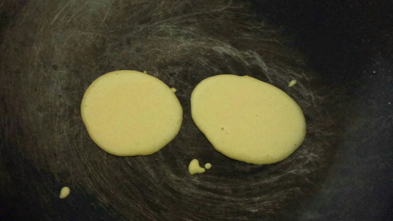 牛奶鸡蛋玉米饼,平底锅微热，用勺子舀一勺面糊垂直倒入，轻轻晃动锅使面糊呈圆形，小火煎﻿