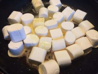 蔓越莓牛轧糖,加入棉花糖，小火慢慢的加热融化，需要不停的搅拌，关火倒入奶粉搅拌均匀。