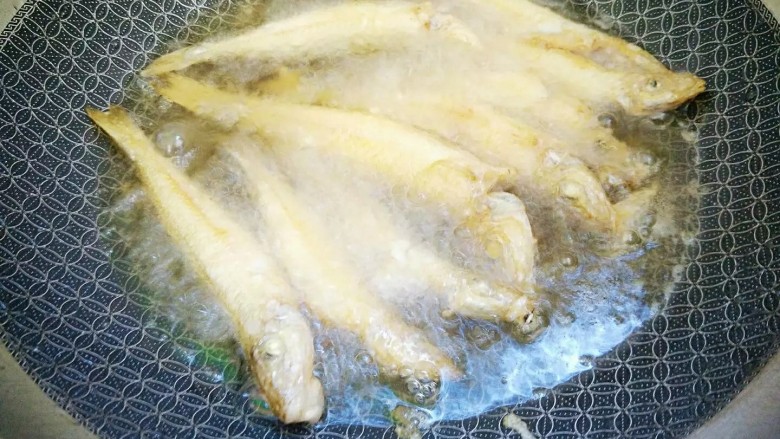 油炸沙尖鱼,将鱼一个一个放入锅，要隔间隙，用筷子不停翻动防止黏连，以文火炸至表面金黄即可。