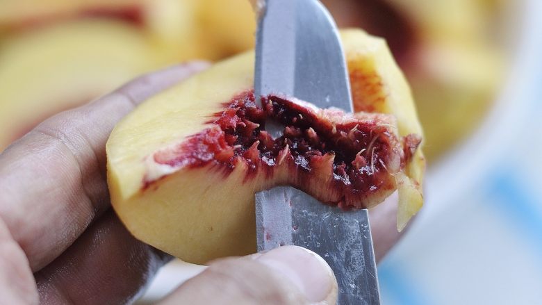 自制黄桃罐头,桃肉切成大块，再把靠近果核处的红褐色口感发苦的桃肉挖掉。