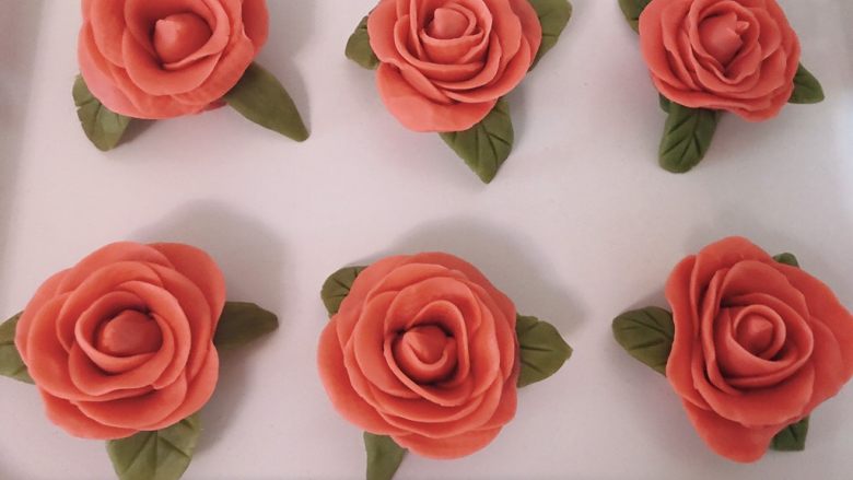 桃山皮玫瑰花月饼,叶子是每朵花3片左右，取适量抹茶桃山皮用手捏出形状，用刮板刻出叶脉即可，在花朵四周贴紧。