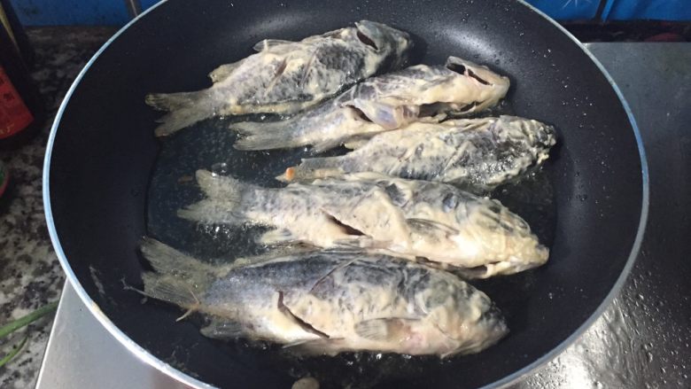 椒盐鲫鱼,等锅里的油温度较高时，把腌制好的鲫鱼放入平底锅里，中小火煎制成两年都是金黄色就可以了。
