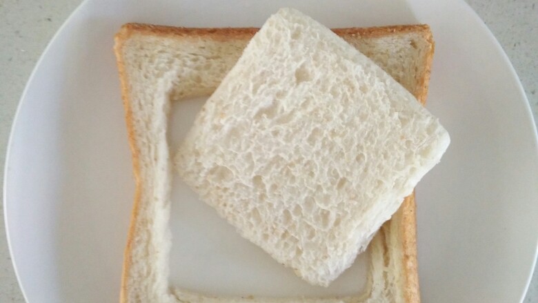 快手早餐——肉松火腿芝士三明治,取一片吐司面包片，用小模具切成如图所示模样。