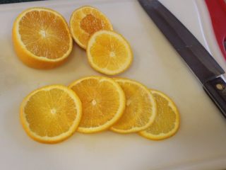 翻转柳橙蛋糕,柳橙洗净切出6片薄片，其余挤出柳橙汁备用。
