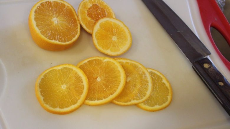 翻转柳橙蛋糕,柳橙洗净切出6片薄片，其余挤出柳橙汁备用。