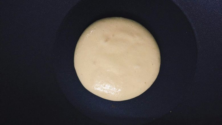 如何轻松制作一个完美的Pancake,用勺子把面糊摊成圆形，注意动作要快点，要不然底面会出来一圈一圈的痕迹，上色就不均匀了。