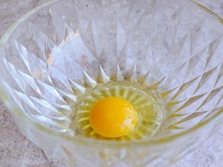 奶香玉米饼,鸡蛋打入碗中