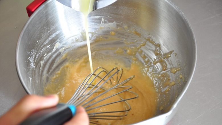 焦糖玛德琳,融化后的黄油加入混合好的面糊中，边加边搅拌。