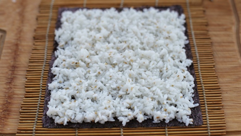金枪鱼寿司,取适量米饭均匀的铺到紫菜上，最上边留一条不放米饭