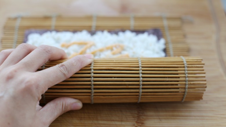 金枪鱼寿司,将竹帘慢慢卷起来，把所有食材包裹进去，在收口处的紫菜上刷一层清水，这样粘的比较牢固
