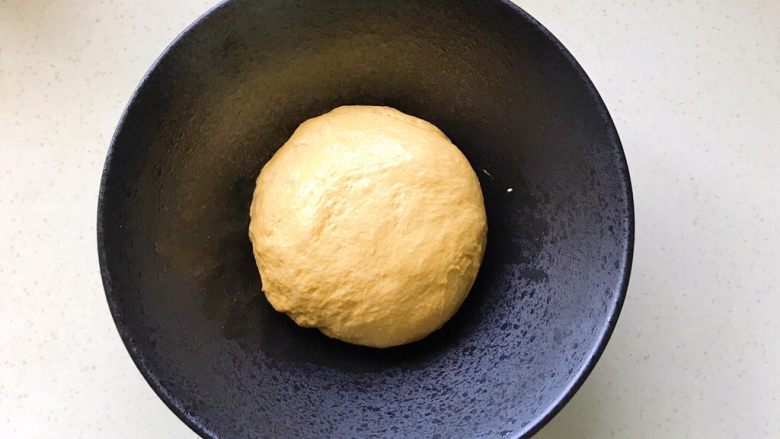 胡萝卜拉丝芝士餐包,取出搓圆放在碗里，包保鲜膜发酵，现在室温发酵就可以了，天气冷可以开启烤箱发酵功能