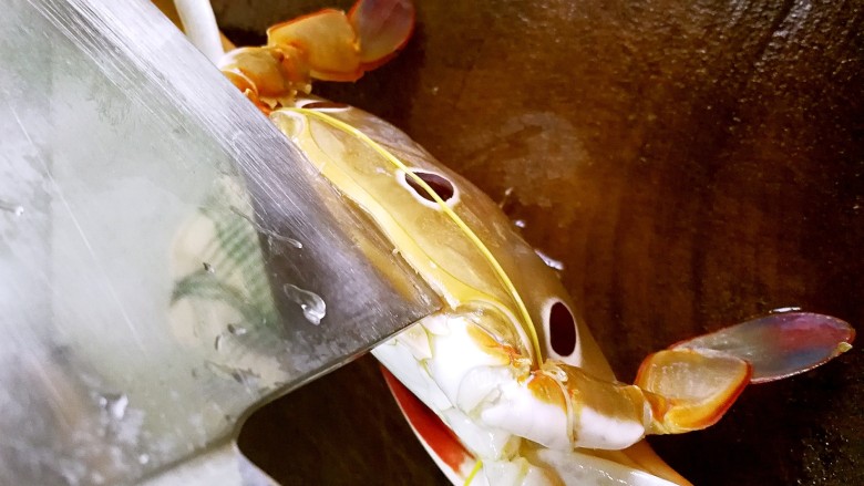 姜葱炒花蟹,用刀尖在蟹盖底部与蟹腹的连接处切开一点，这样蟹就基本不会乱动，可以把皮筋或绳子取下了。