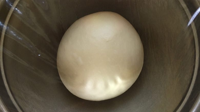 蜜豆酸奶手撕小面包,面团两手托着，大拇指和四指配合向内收面团至面团表面光滑成球状，放入盆内，盖保鲜膜室温发酵二倍大。