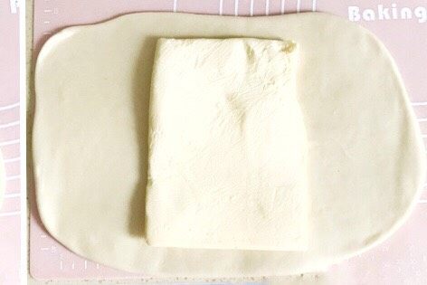 万能千层酥皮,面皮擀好后，从冰箱取出一片黄油，将黄油摆放在面皮的中间位置
