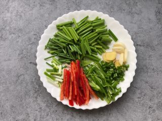 家常小炒肉丝,韭菜苔切小段，青红椒切丝、蒜瓣和姜切片、葱切小段