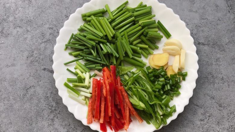 家常小炒肉丝,韭菜苔切小段，青红椒切丝、蒜瓣和姜切片、葱切小段