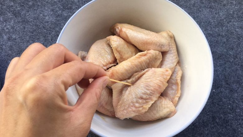 盐焗鸡中翅～烤箱版,鸡中翅放入盘中，用牙签逐个在上面撮上小洞，让其更好腌制入味。