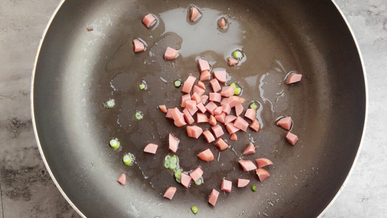 海苔芝士肉松饭团,锅里入油，放入葱花和火腿肠炒香