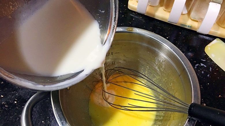 美味卡士达小餐包
（附卡士达酱做法）,煮热后的牛奶缓慢的倒入蛋黄糊中，蛋抽搅拌