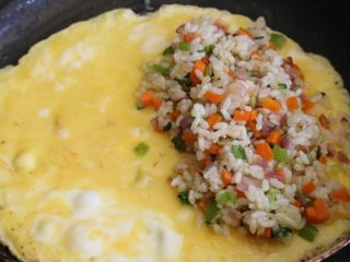 日式蛋包饭,倒入鸡蛋液摊平，煎至无蛋液后，在一边铺上炒好的米饭。