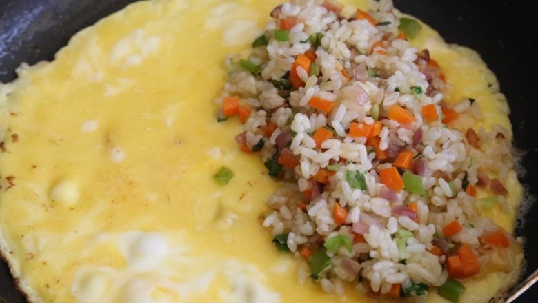 日式蛋包饭,倒入鸡蛋液摊平，煎至无蛋液后，在一边铺上炒好的米饭。