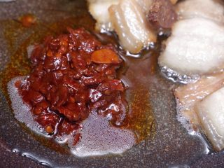 川味回锅肉,将肉片推倒锅边，放1勺郫县豆瓣酱；