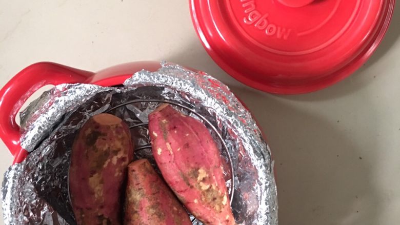 坤博砂锅烤红薯,红薯摆放在砂锅里烤架上。