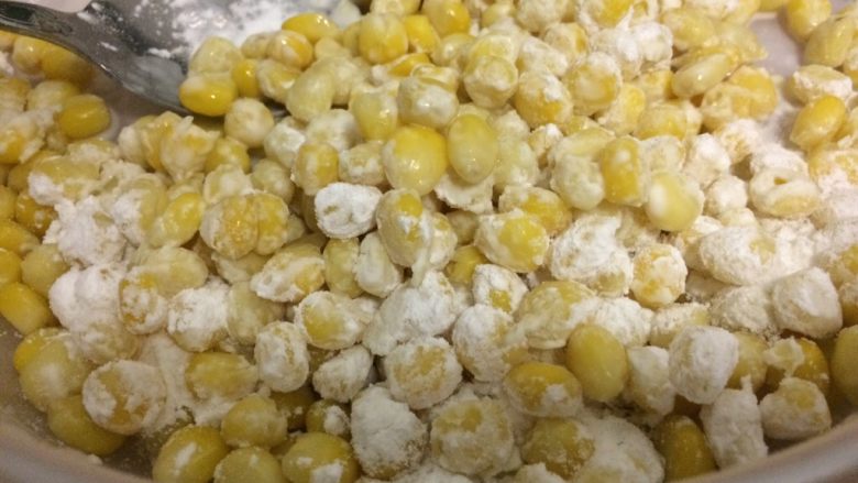 金沙玉米,把玉米淀粉倒入玉米粒中，使玉米粒均匀沾上粉。