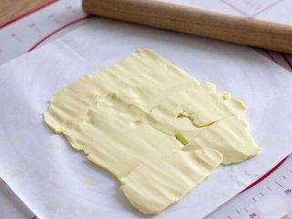 美味好吃的拿破仑,趁着面团松弛的时间，将要裹的黄油用油纸垫着，排成长方形的模样，再用擀面杖敲打变软，可以按出手印即可；（夏天如果太软，可以再放冰箱冷藏一小会）