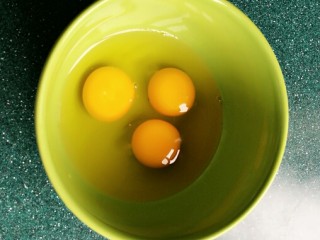 茴香鸡蛋花边菜饼,碗里打入三个鸡蛋，蛋液搅拌均匀。