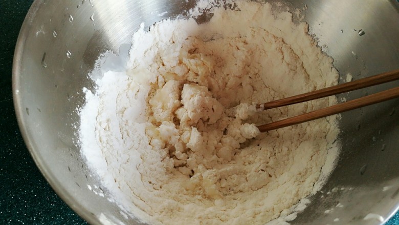 茴香鸡蛋花边菜饼,尽量搅拌到没有干粉为止，然后盖个盖子等烫过的面絮稍微冷却一下，用手揉成面团。