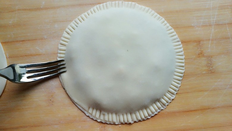 茴香鸡蛋花边菜饼,用叉子在饼皮四周按压出纹路。