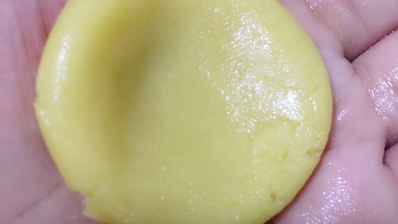广式月饼——莲蓉蛋黄馅,分割饼皮15g一个，将饼皮用大拇指把中间压扁。