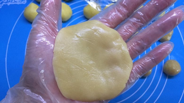 自制奶黄馅广式小月饼,取一个面团，用右手手掌压扁