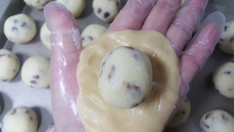 椰蓉枸杞月饼,16.取一份饼皮压扁后包入一份椰蓉馅。