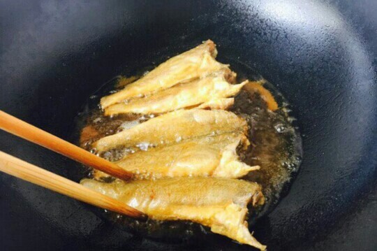 小黄鱼焖豆腐,锅里放入适量的油，小黄鱼两面裹上面糊待油6成热的时候，把裹好面糊的小黄鱼，轻轻地贴着油面放入锅里。
