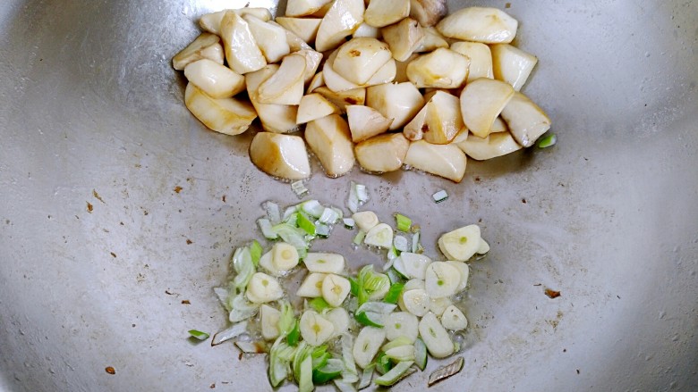 三汁杏鲍菇,用铲子把煎好的杏鲍菇铲到锅的一边，另一边放入葱蒜爆香。