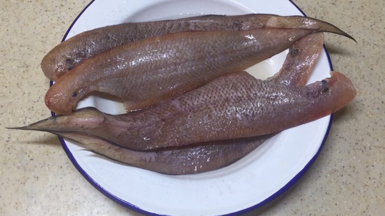 水煮龙舌鱼,将龙舌鱼刮去鱼鳞，剪去肚子洗净，加入盐腌制5分钟。