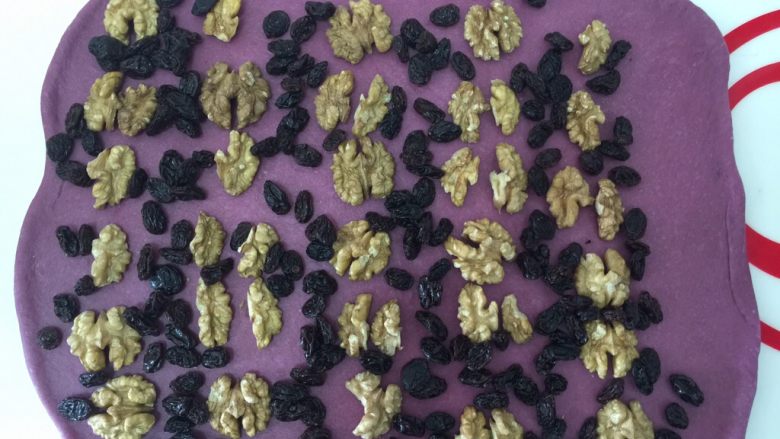 紫薯大列巴,把核桃和葡萄干排列好。
正常来说，传统的大列巴用的是青提子干，我孩子喜欢黑提子干，所以没办法🤣
一边留出5cm左右的空位